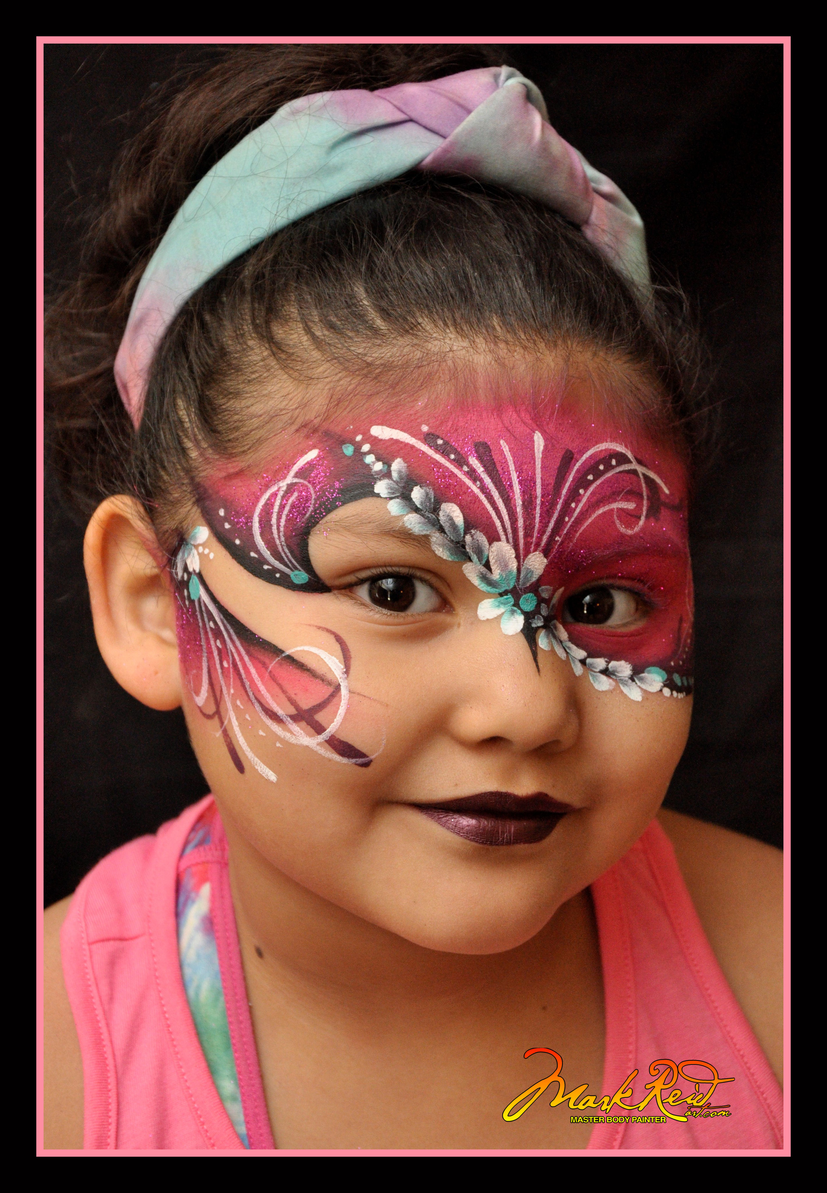 youg girl wearing a painted on mask that is pink with nice highlights that matches the shirt she is wearing