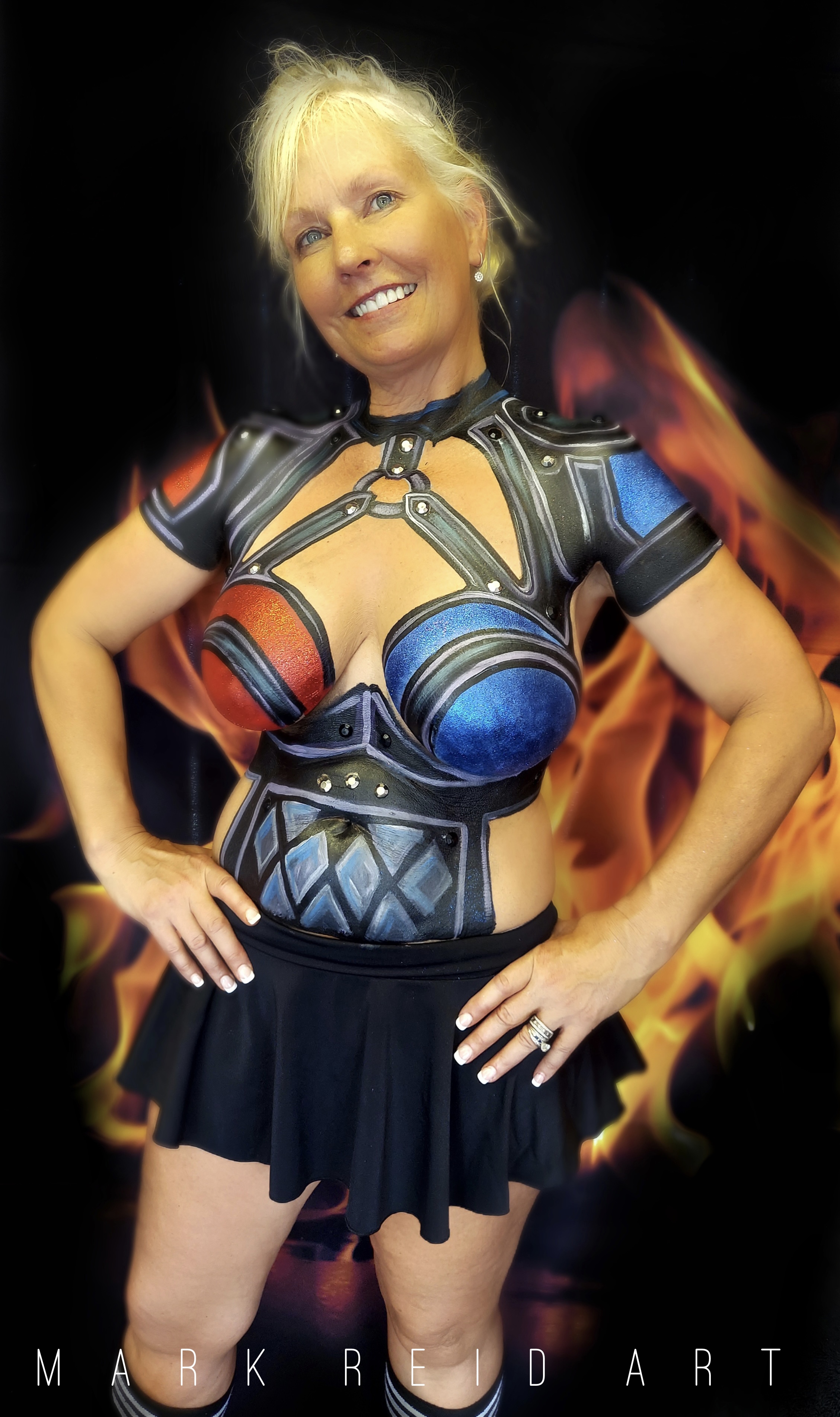 Blonde woman with a painted on top that is red, blue, and black. The black portions look like detailed black leather. Red and blue cover the breasts and shoulders, one color per side.